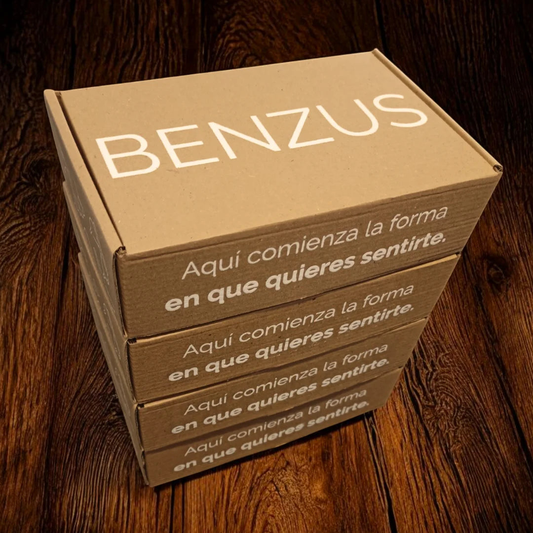 Pila de cajas de envío premium de la marca BENZUS. Empaque de cartón kraft ecológico con el logo en blanco y el eslogan repetido en el lateral: 'Aquí comienza la forma en que quieres sentirte'. Presentación de lujo para ropa interior masculina.